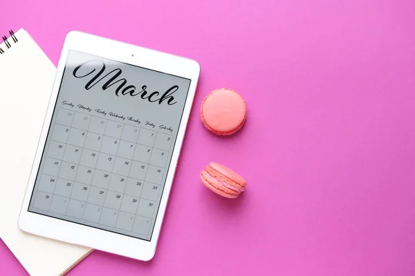 Tablet PC med kalender på skärmen, kakor och anteckningsbok på färg bakgrund — Stockfoto