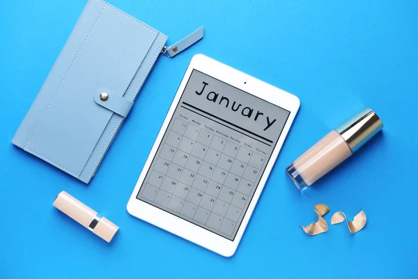 Tablet ordenador con calendario en pantalla, cosméticos y billetera sobre fondo de color —  Fotos de Stock