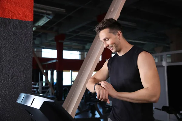 Sporty young man with fitness tracker training on treadmill in gym — Stock Photo, Image
