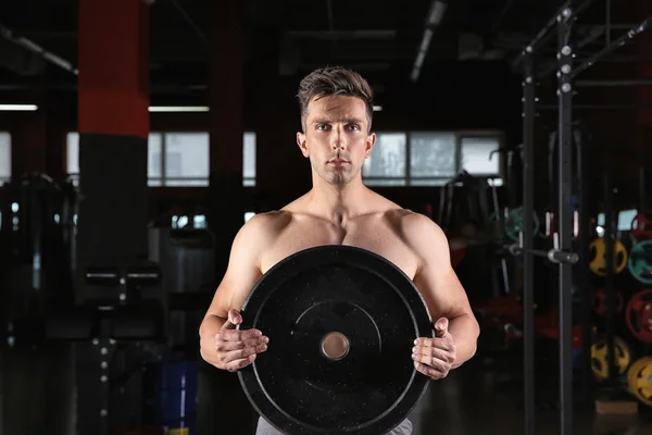 Sporty young man training with weight plate in gym — Stock Photo, Image