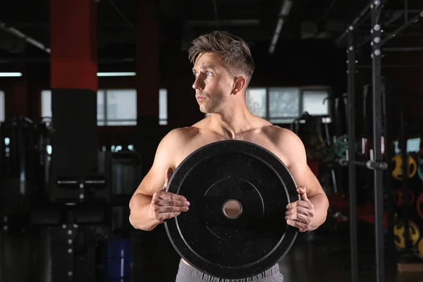 Sporty young man training with weight plate in gym — Stock Photo, Image