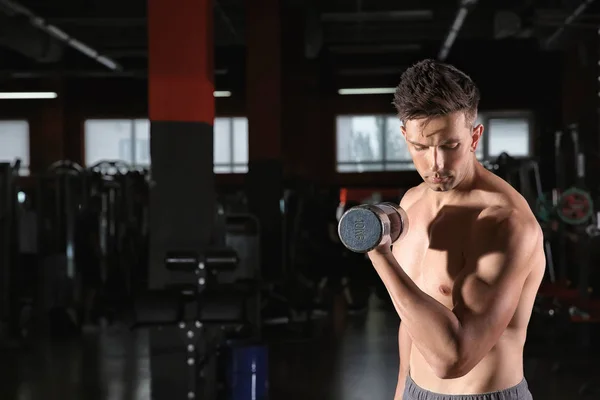 Sporty young man with dumbbells in gym — Stock Photo, Image