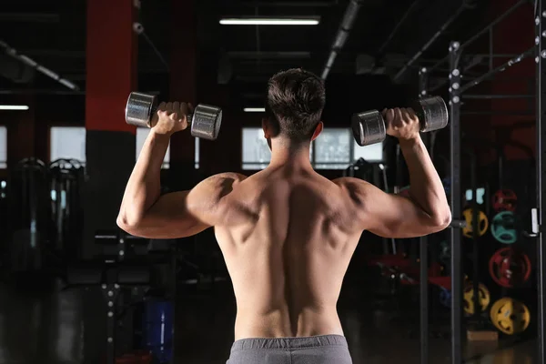 Jeune homme sportif avec haltères dans la salle de gym — Photo