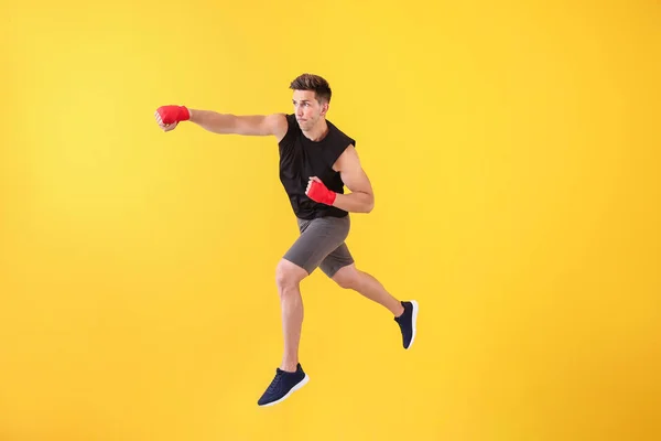 Спортивный кикбоксер мужского пола на цветном фоне — стоковое фото