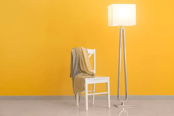 Elegante lámpara con silla cerca de la pared de color — Foto de Stock