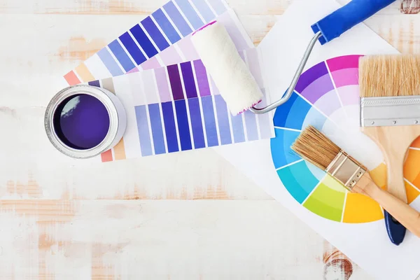 Can of paint with supplies and palette samples on light background — Stock Photo, Image