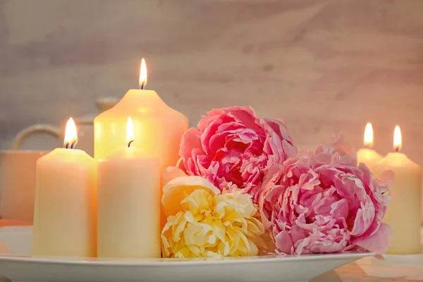 Plate with beautiful burning candles and flowers on table — Stock Photo, Image