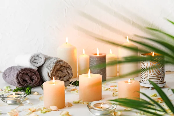 Beautiful spa composition with burning candles and towels on table — Stock Photo, Image