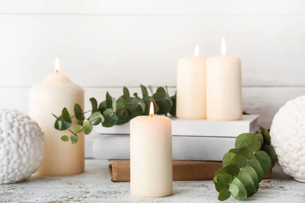 Beautiful burning candles with eucalyptus and books on light background — Stock Photo, Image