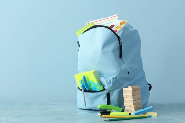 Renk arkaplanında kırtasiye malzemesi olan okul çantası