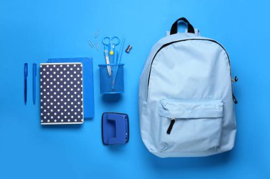 Renk arkaplanında kırtasiye malzemesi olan okul çantası