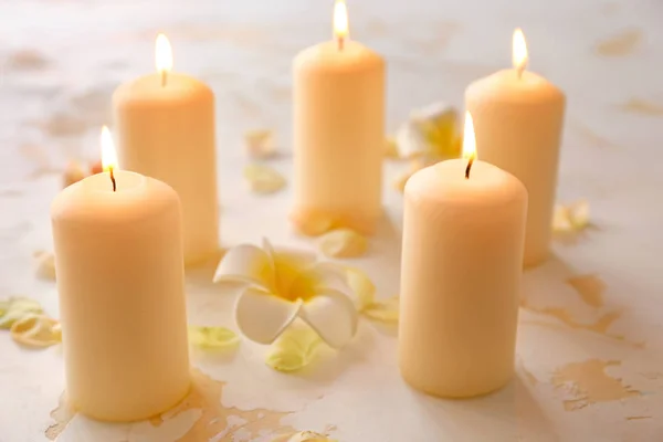Égő gyertya és szép virágszirmok az asztalon — Stock Fotó