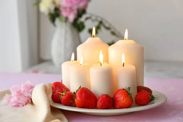 Plate with beautiful burning candles and strawberries on table — Stock Photo, Image