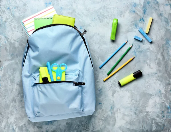 Mochila escolar con papelería sobre fondo de color — Foto de Stock