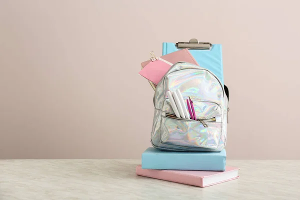 School backpack with stationery on table against light background — Stock Photo, Image