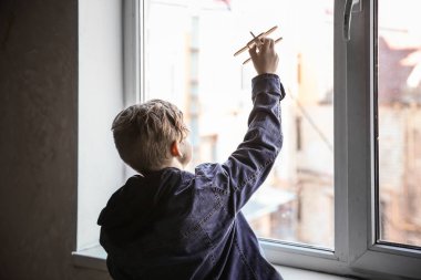 Evsiz küçük çocuk pencere kapalı yakın uçak ile oynuyor