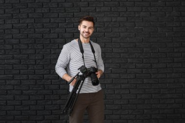 Karanlık arka planda genç erkek fotoğrafçı