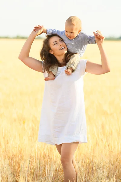 Gyönyörű nő játszik a búzamező fiával nyári napon — Stock Fotó