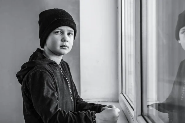 Niño sin hogar cerca de la ventana interior — Foto de Stock