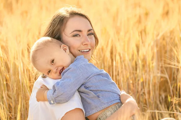 Beautiful woman with her little son in wheat field on summer day — Stock Photo, Image