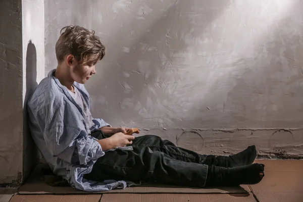 Petit garçon sans abri avec du pain assis sur le sol — Photo