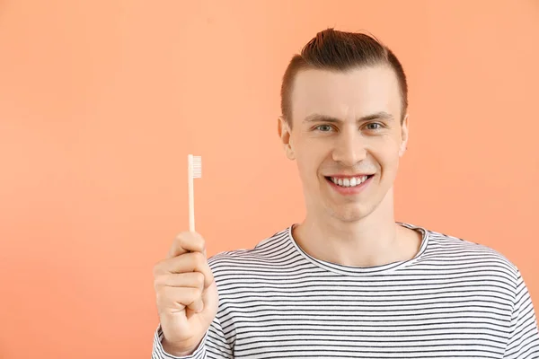 Happy man with toothbrush on color background — Stock Photo, Image