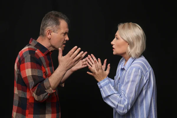 Quarrelling middle-aged couple on dark background — Stock Photo, Image