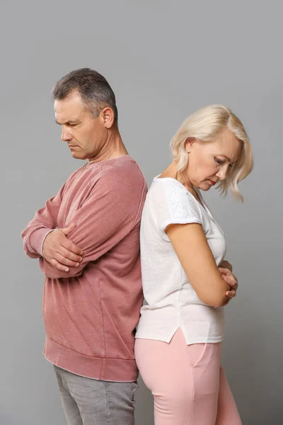 Sad middle-aged couple after quarrel on grey background — Stock Photo, Image