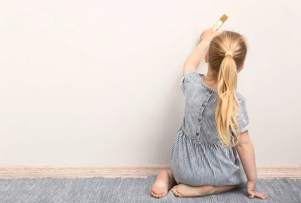 Little girl painting on light wall — Stock Photo, Image