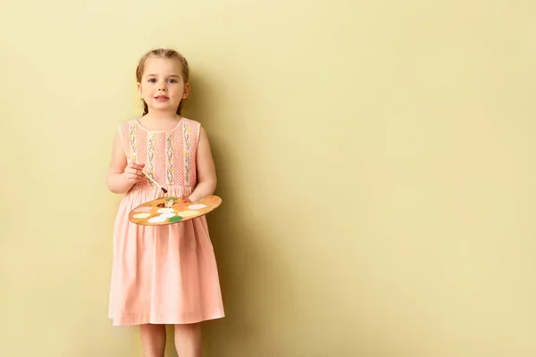 Renk duvara yakın fırça ve palet ile küçük kız — Stok fotoğraf