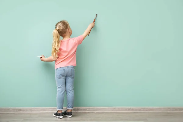Маленькая девочка рисует на цветной стене — стоковое фото