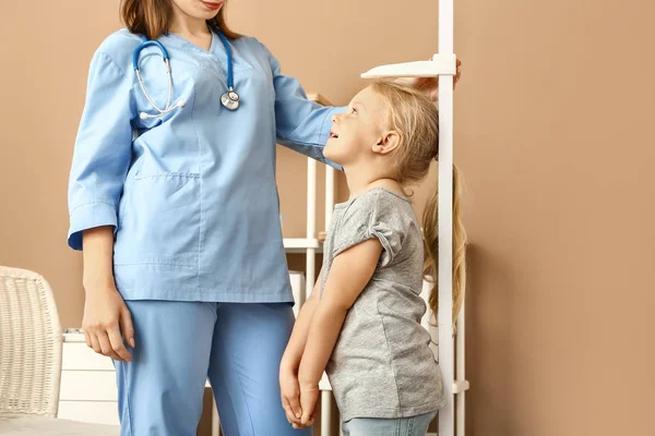 Female nurse measuring height of little girl in hospital — Stock Photo, Image