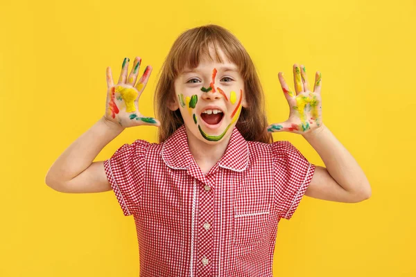 Funny little girl with hands and face in paint on color background — Stock Photo, Image