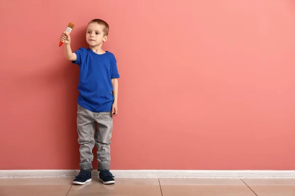 色の壁の近くにブラシを持つ小さな男の子 — ストック写真