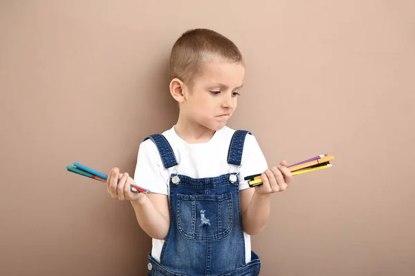 Mały chłopiec wybiera ołówki do rysowania na kolorowym tle — Zdjęcie stockowe