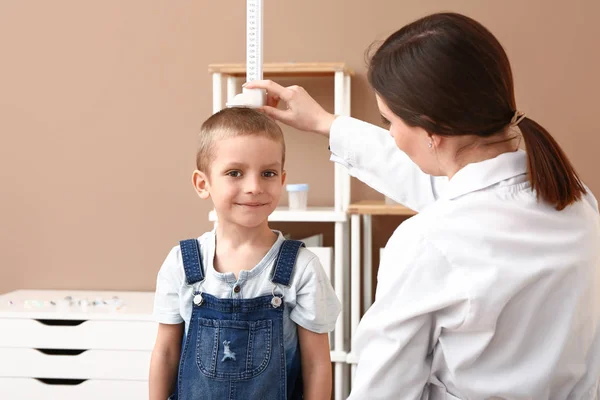 Женщина-врач измеряет рост маленького мальчика в больнице — стоковое фото