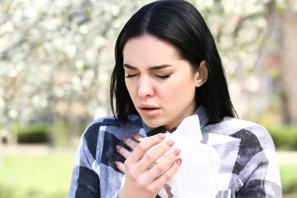 Young woman with nose wiper near blooming tree — Stock Photo, Image