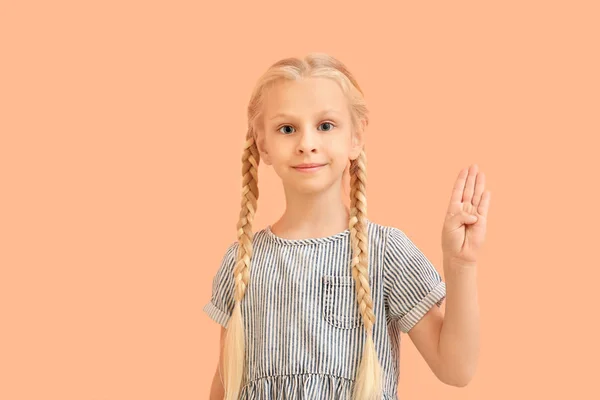 Little deaf mute girl using sign language on color background