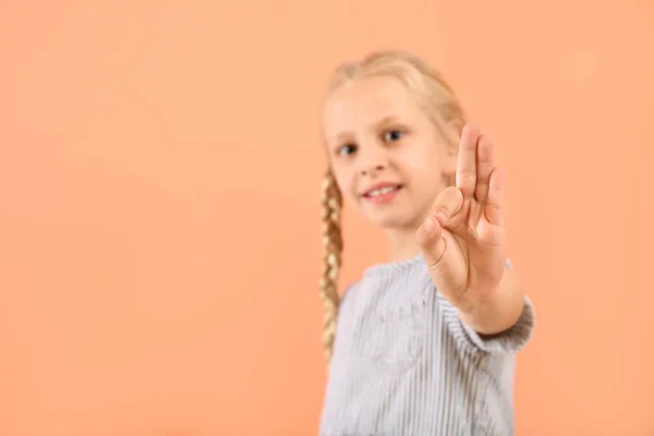 Pequena menina surda muda usando linguagem de sinais no fundo de cor — Fotografia de Stock