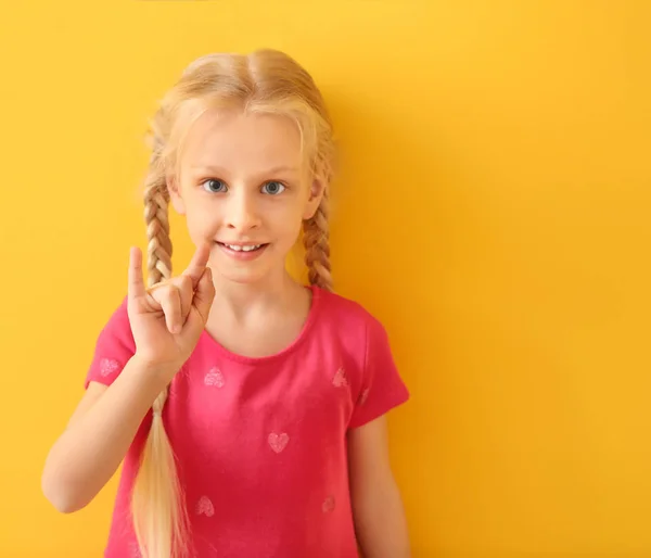 Little deaf mute girl using sign language on color background — Stock Photo, Image