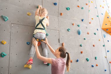 Eğitmen küçük kız spor salonunda duvara tırmanmaya yardım