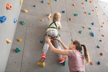 Eğitmen küçük kız spor salonunda duvara tırmanmaya yardım