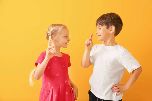 Little deaf mute children using sign language on color background