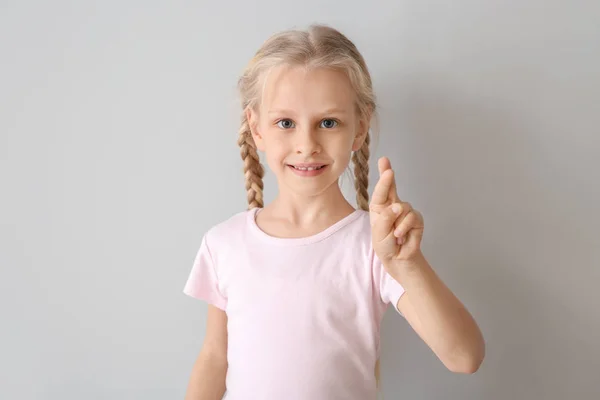 Little deaf mute girl using sign language on light background — Stock Photo, Image