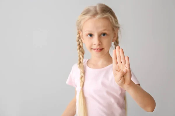 Weinig doof Mute meisje met gebarentaal op lichte achtergrond — Stockfoto
