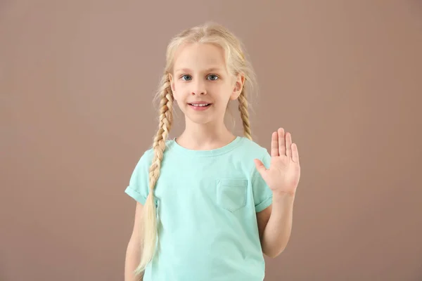 Little deaf mute girl using sign language on color background