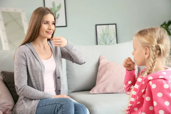 Mother teaching her deaf mute daughter to use sign language at home — Stock Photo, Image