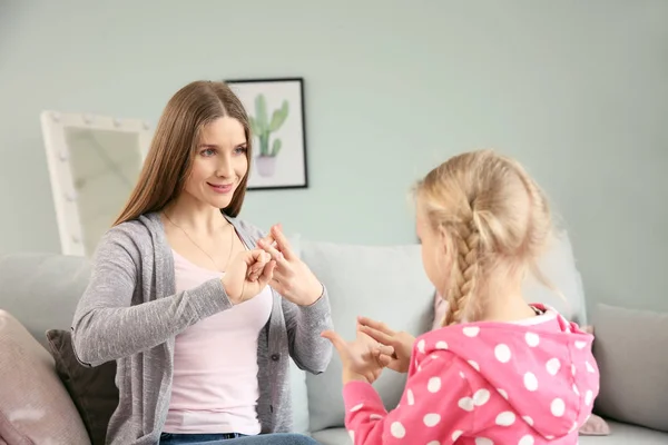 Mother teaching her deaf mute daughter to use sign language at home — Stock Photo, Image