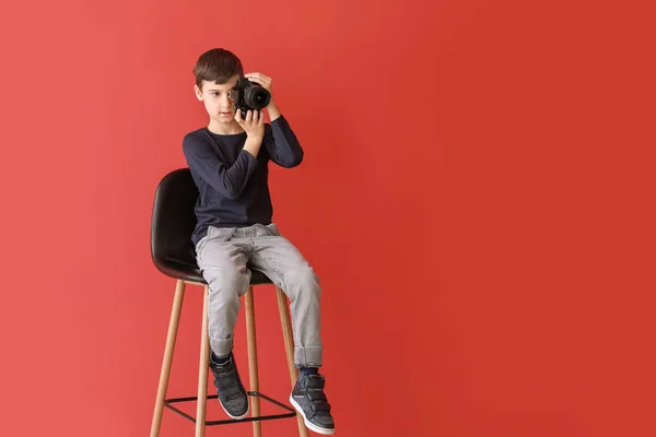 Lindo fotógrafo sentado en la silla contra el fondo de color — Foto de Stock