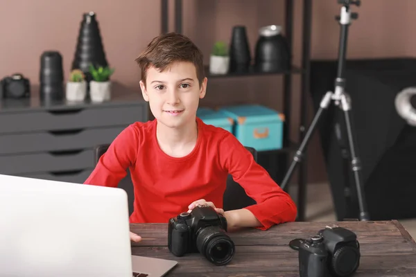 Cute little photographer sitting at table in professional studio